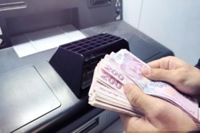 A person counting 200 TL banknotes in front of an ATM
